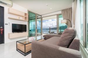 a living room with a couch and a television at Elegant 2BR Oceanview Condo Oceana C73 - 5 min walk Kamala Beach in Kamala Beach