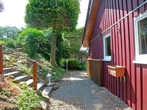 a red house with a walkway next to a building at Holiday Home Zedernhütte by Interhome in Bremke