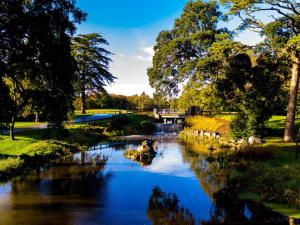 a river in a park with a bridge in the background at Holiday Home Castlemartyr Lodges - TR4 No 20 - 2 Bed by Interhome in Castlemartyr