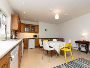 a kitchen with a table and yellow chairs in a kitchen at Holiday Home An Searrach Holiday Home Dingle by Interhome in Dingle