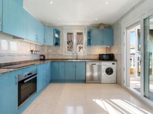 eine Küche mit blauen Schränken und einer Waschmaschine und einem Trockner in der Unterkunft Villa Villa Recorral by Interhome in Rojales