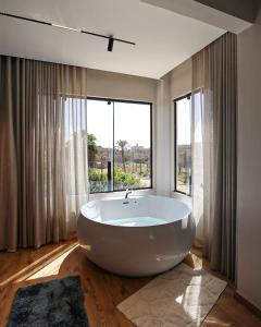 a large white bath tub in a room with windows at Palacio Pyramids Hotel in Cairo +59 photos