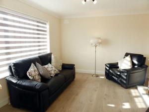 - un salon avec un canapé noir et deux chaises dans l'établissement Holiday Home Bolams - TR2 Holiday Home by Interhome, à Thomastown