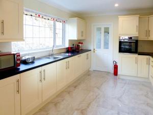 une cuisine avec des placards blancs et une grande fenêtre dans l'établissement Holiday Home Bolams - TR2 Holiday Home by Interhome, à Thomastown