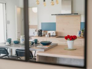 a kitchen with a table with a vase of red roses at Holiday Home Bol d'Air by Interhome in Ploubalay