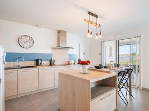 a kitchen with white cabinets and a clock on the wall at Holiday Home Bol d'Air by Interhome in Ploubalay +14 photos