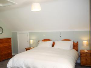 Un dormitorio con una gran cama blanca con dos mesitas de noche. en Holiday Home Dunmore Villas Holiday Home No 1 by Interhome, en Dunmore East