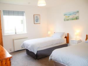 Un dormitorio con dos camas y una ventana. en Holiday Home Dunmore Villas Holiday Home No 1 by Interhome, en Dunmore East