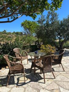a patio with a table and chairs and trees at A Casuzza di Poggio Scopello in Scopello