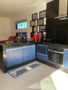 a kitchen with blue cabinets and a black counter top at Faith Home 1 in Arraial do Cabo