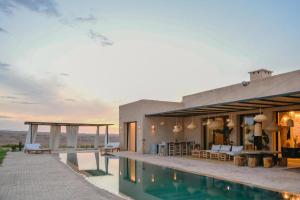a villa with a swimming pool in the desert at Palais Maya in Id Aïssa