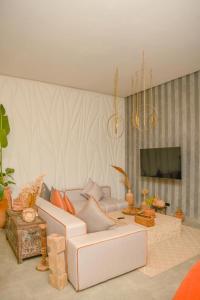 uma sala de estar com um sofá branco e uma TV em Palais Maya em Id Aïssa