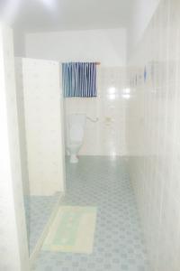 Un baño blanco con inodoro y ducha. en Mwazhouse, en Watamu