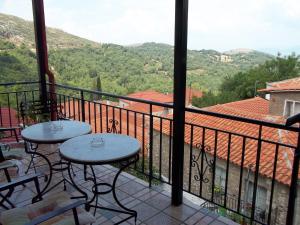 a balcony with two tables and a view of the mountains at Epikoureios Apollon in Andritsaina