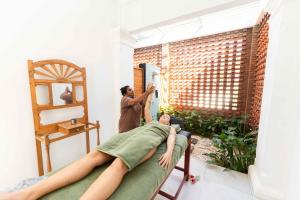a woman cutting a persons legs on a bed at Ocean Gateway Dickwella in Dickwella