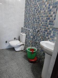 a bathroom with a toilet and a sink and a bucket at Priyakant palace in Chhatikara