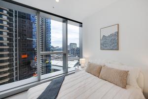 a bedroom with a white bed and a large window at CBD Elegant 2BR Apt with Pool, Gym & City Views in Melbourne +13 photos
