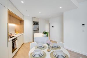 a kitchen with a table with bowls and plates on it at CBD Elegant 2BR Apt with Pool, Gym & City Views in Melbourne