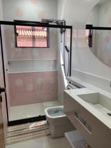 a bathroom with a toilet and a sink and a mirror at Faith Home 1 in Arraial do Cabo +30 photos