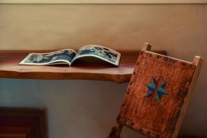 an open book on a wooden shelf next to a chair at Na Floresta Glamping in Pôrto de Pedras