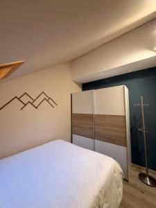 a bedroom with a white bed and a cross on the wall at Acogedor Ático en el Corazón de Formigal - Esquía sin llaves in Formigal
