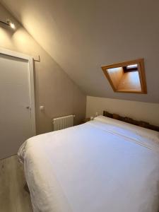 a bedroom with a large white bed with a skylight at Acogedor Ático en el Corazón de Formigal - Esquía sin llaves in Formigal +26 photos
