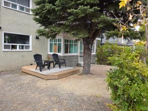 dos sillas y una mesa frente a una casa en Cozy 2-bedroom Downtown Apartment Campbellton Walk to Cafés & Shops, en Campbellton