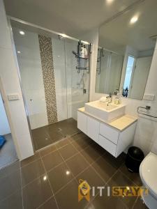 une salle de bain avec un lavabo blanc et une douche dans l'établissement Tranquil, Relaxing Forrest Style Apartment - Braddon CBD, à Canberra 9 autres photos