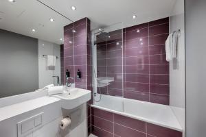a bathroom with a sink and a shower with purple tiles at Premier Inn Regensburg City Centre in Regensburg +16 photos