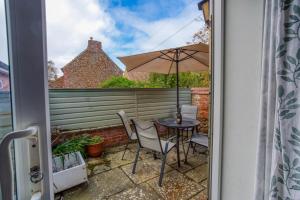 eine Terrasse mit Tisch und Sonnenschirm in der Unterkunft Waders - 2 bedroom coastal retreat, Crabpot Cottages, Hunstanton in Hunstanton