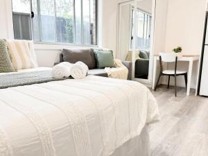 a white bedroom with a bed and a living room at North Wollongong - Beach Style - Modern - Free Parking - Free Coffee Snacks in Woonona