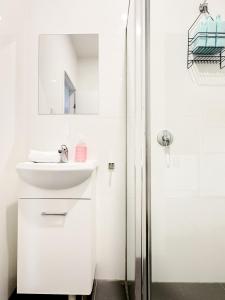 a white bathroom with a sink and a shower at North Wollongong - Beach Style - Modern - Free Parking - Free Coffee Snacks in Woonona