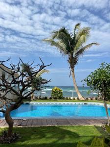 a swimming pool with palm trees and the ocean at Oasis luxueuse en bord de Mer Virage Dakar in Dakar