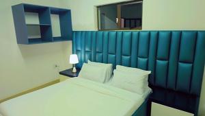 a bed with a blue headboard in a bedroom at Jabulani Lodge in Johannesburg +1 photo