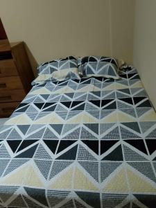 a bed with a black and white quilt on it at Edifício thorium in Guarapari