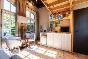 Una cocina con gabinetes blancos y una mesa y sillas. en Le Parc de Louette - Le Pavillon - Esc'Appart, en Gedinne