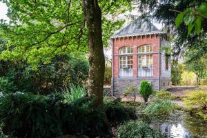 un edificio de ladrillo con una ventana en un jardín en Le Parc de Louette - Le Pavillon - Esc'Appart, en Gedinne