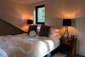 1 dormitorio con 1 cama blanca con 2 lámparas y una ventana en The Treehouse Hideaway, 