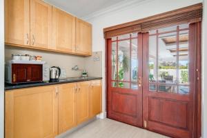 a kitchen with wooden cabinets and a red door at #5A on Brassie in Lakeside