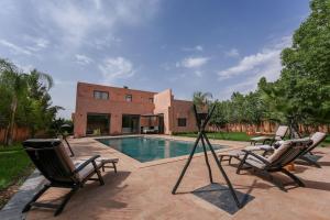 a swimming pool with two lawn chairs and a telescope at Villa Dar El Gharrabia in Amezrou