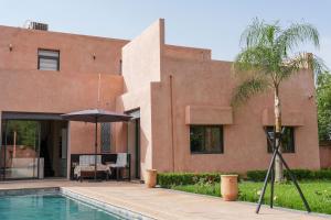 a house with a swimming pool and an umbrella at Villa Dar El Gharrabia in Amezrou