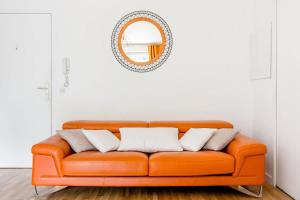 an orange couch in a room with a mirror at Passion et détente by UTA HOUSE in Saint-Denis