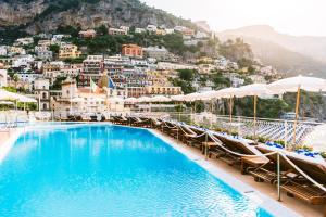 a pool with chairs and umbrellas in front of a city at Covo Dei Saraceni in Positano