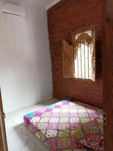 une chambre avec une courtepointe sur le sol et une fenêtre dans l'établissement Joglo Hexa, à Bugisan