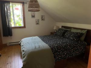ein Schlafzimmer mit einem Bett und einem Fenster in der Unterkunft La maison des Coteaux in LʼAnse-Saint-Jean
