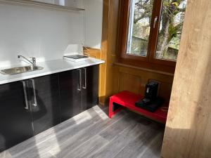 een keuken met een rode bank met een spoelbak en een raam bij Le séjour in Tramelan
