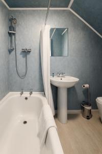 a bathroom with a white tub and a sink at The Anchorage in Troon