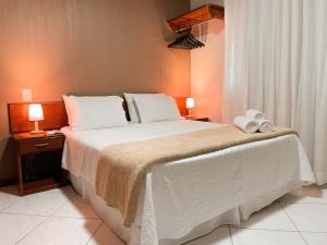 a bedroom with a large white bed with two lamps at Hotel Fazenda China Park in Pedra Azul