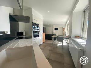 a kitchen with white cabinets and a dining room at Gîte de la Anse sur Pareloup in Arvieu +10 photos