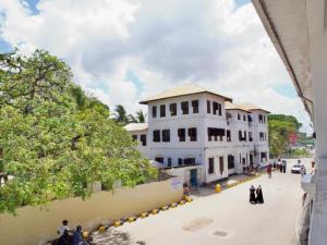 eine Gruppe von Menschen, die vor einem Gebäude eine Straße hinuntergehen in der Unterkunft Mkunazini Heritage Hostels in Zanzibar City + 18 Fotos